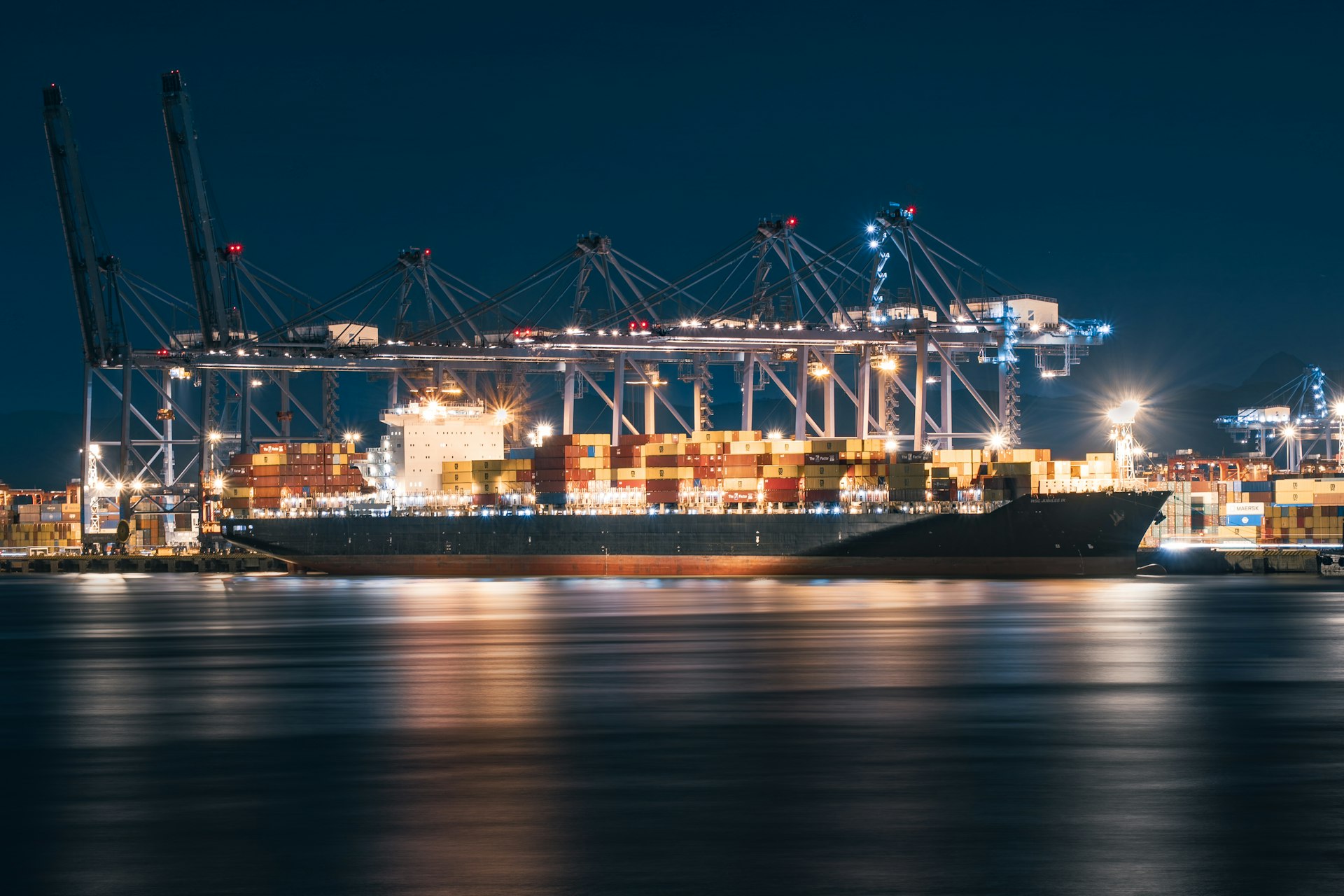 Cargo ship docked at a busy port at night